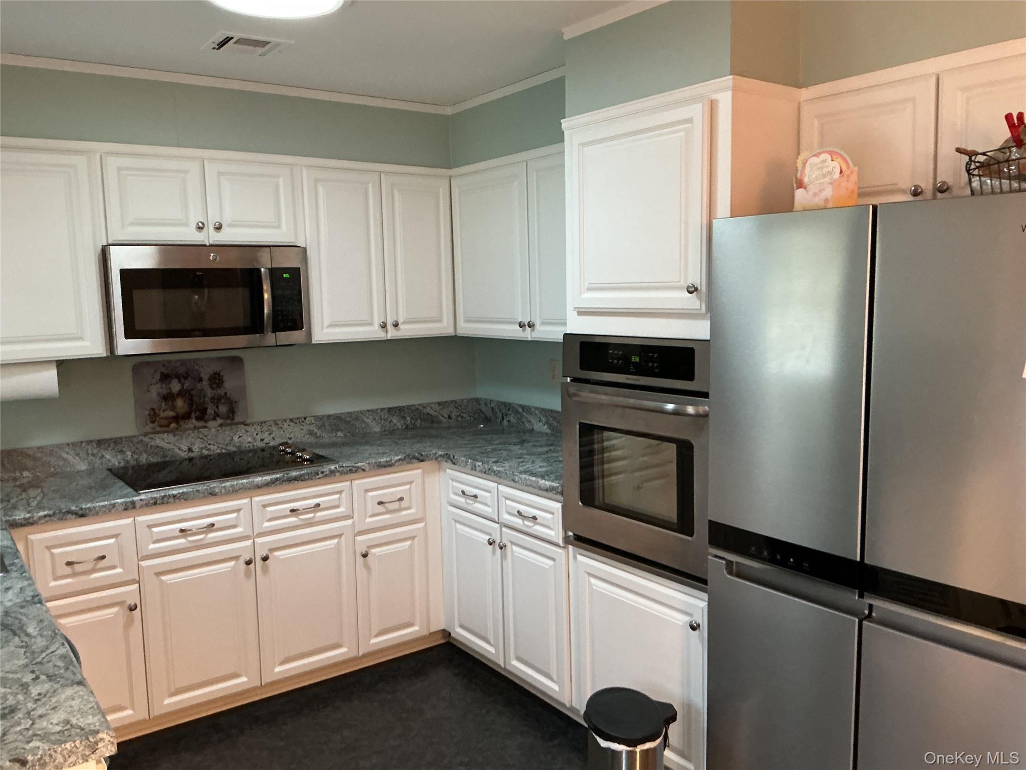 207 Woodbridge Drive, Unit B Ridge, NY 11961 - Photo 5 of 22 a kitchen with granite countertop white cabinets and stainless steel appliances