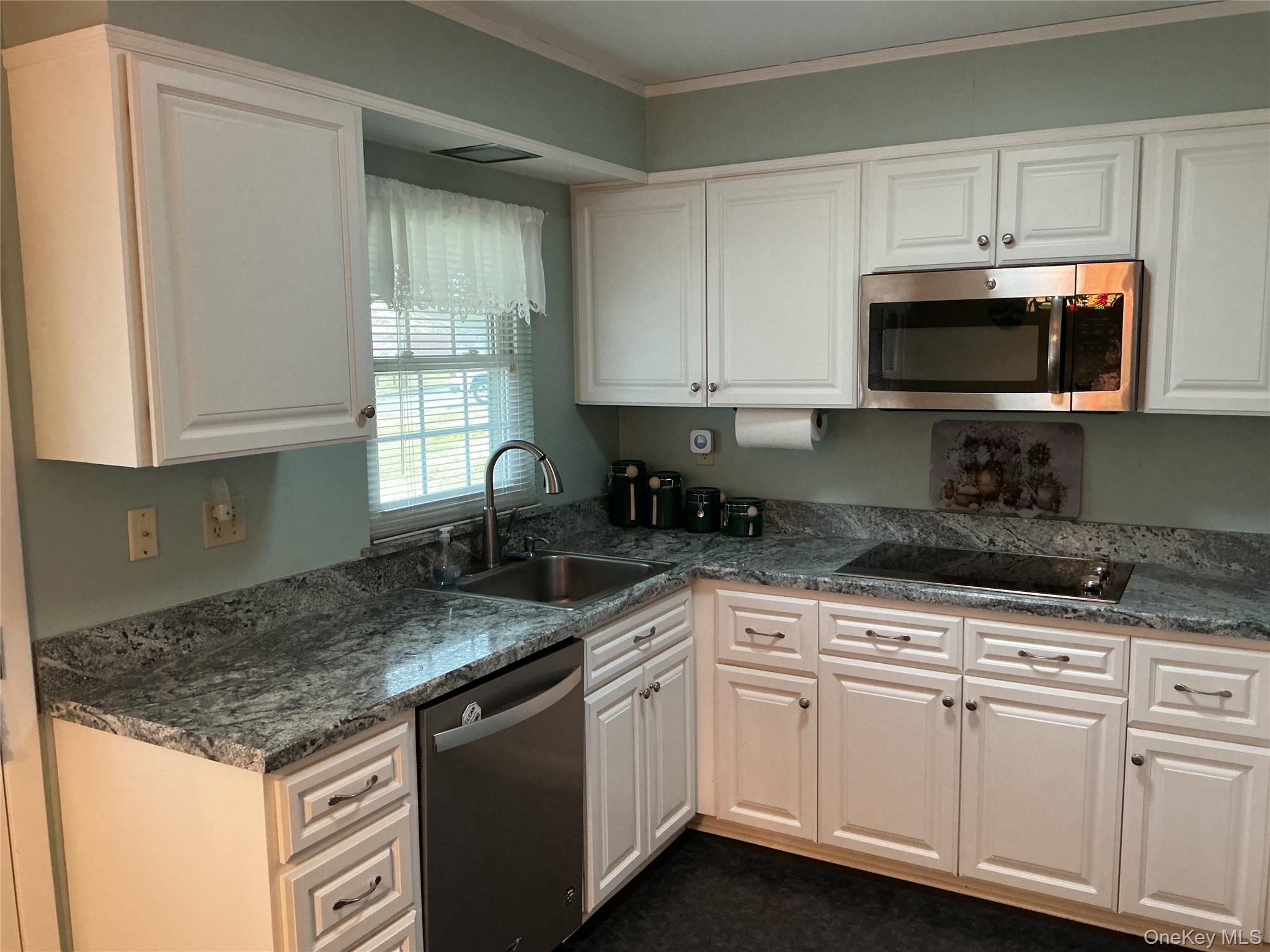 207 Woodbridge Drive, Unit B Ridge, NY 11961 - Photo 6 of 22 a kitchen with granite countertop a sink stainless steel appliances and white cabinets