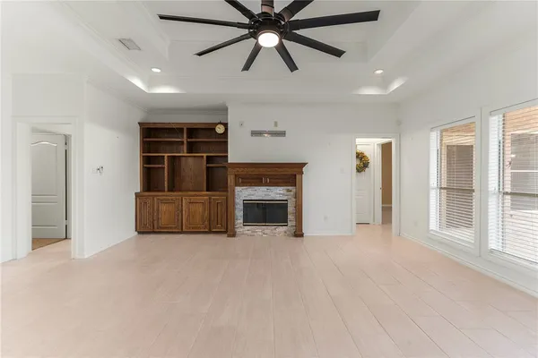 a view of a livingroom with a ceiling fan a fireplace and windows