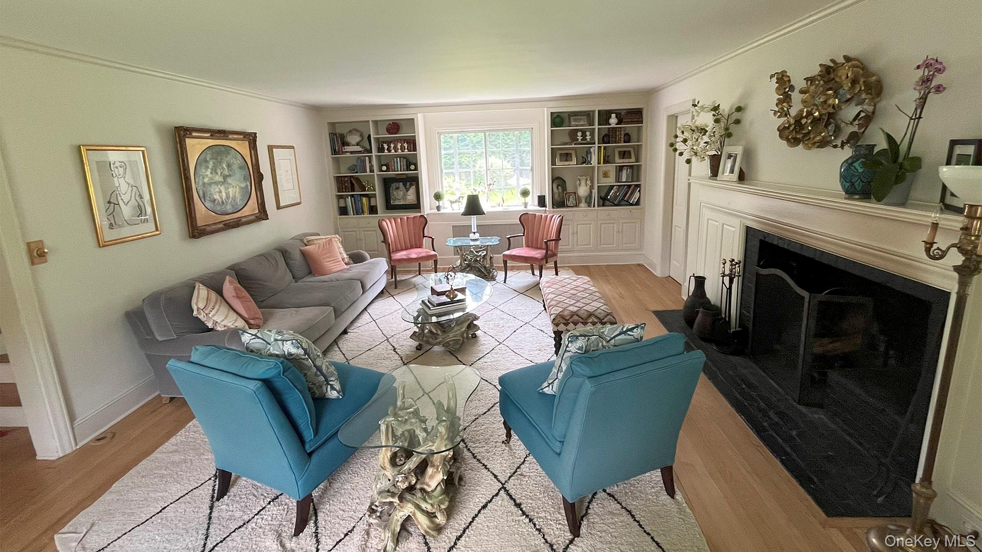 8 Holly Lane Rye, NY 10580 - Photo 13 of 27 Living room featuring wood finished floors, built in shelves, ornamental molding, and a fireplace with flush hearth