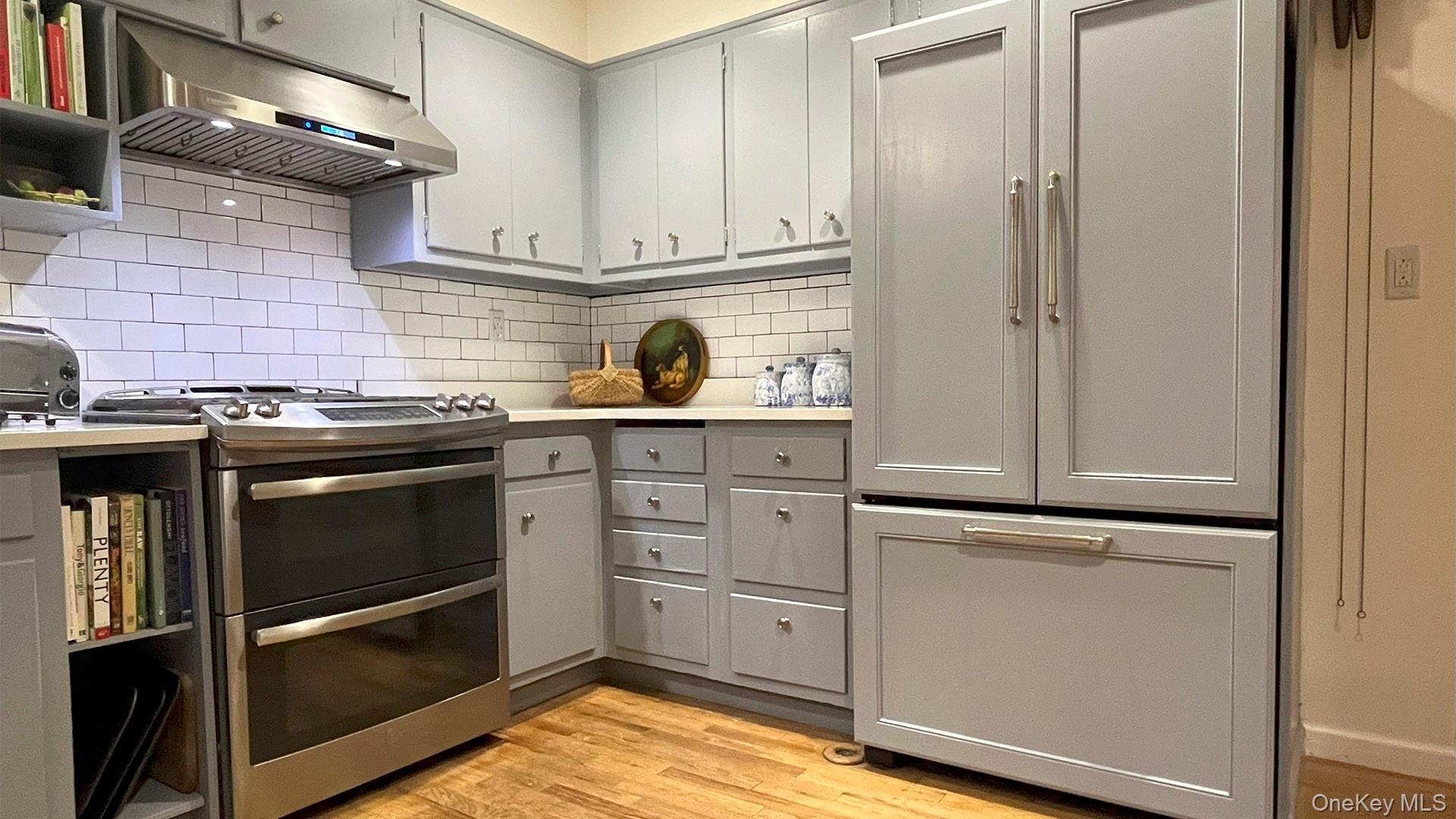 8 Holly Lane Rye, NY 10580 - Photo 4 of 27 Kitchen featuring range with two ovens, under cabinet range hood, gray cabinetry, light countertops, and light wood-type flooring