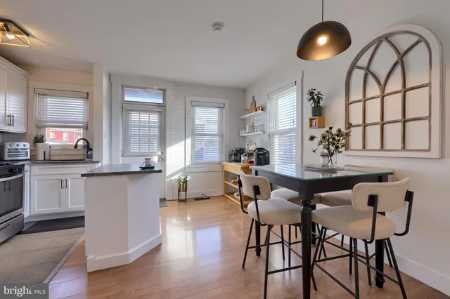 a kitchen with stainless steel appliances granite countertop a dining table chairs and white cabinets