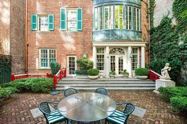 a view of a backyard with table and chairs potted plants and a large tree