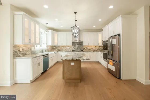 a large kitchen with granite countertop a sink and white cabinets