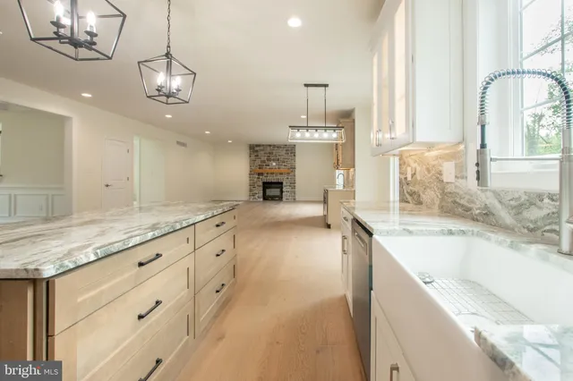 a large kitchen with granite countertop a large counter top a sink stainless steel appliances and cabinets