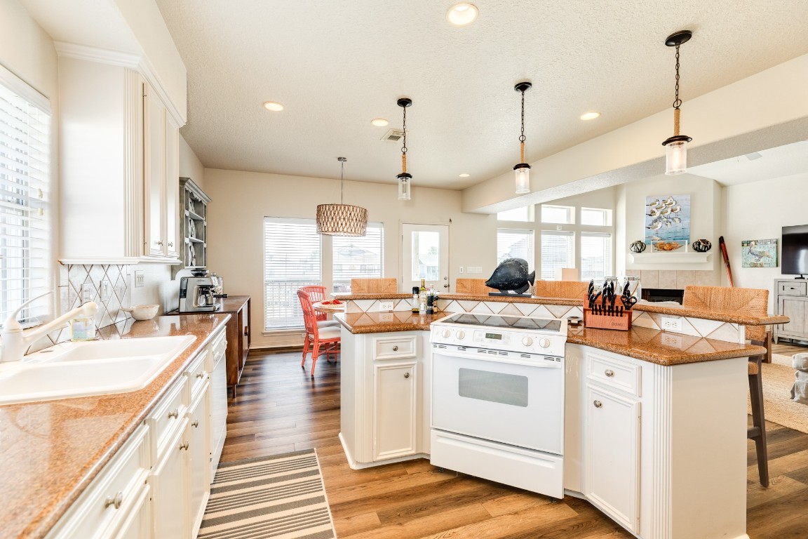 1319 Coral Way Tiki Island, TX 77554 - Photo 36 of 45 a kitchen with a stove oven and white cabinets with wooden floors