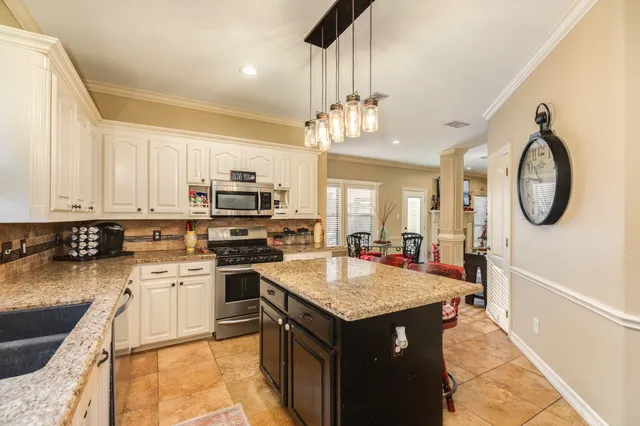 a kitchen with a stove cabinets a sink a dining table and chairs
