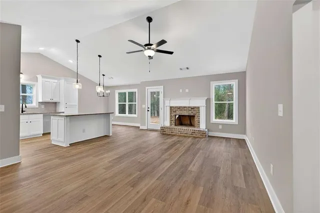 a view of kitchen and empty room with wooden floor fireplace