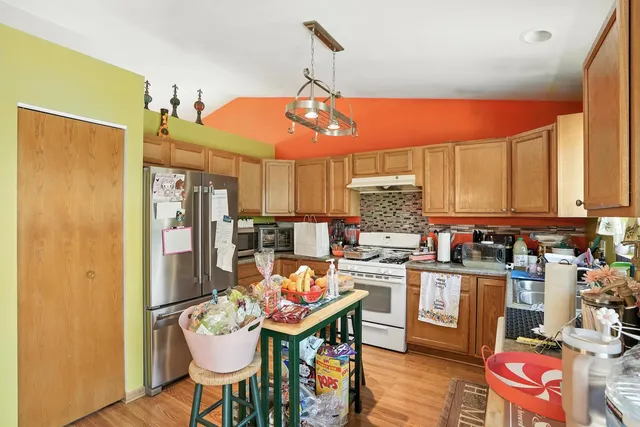 a kitchen with stainless steel appliances a dining table chairs refrigerator and sink