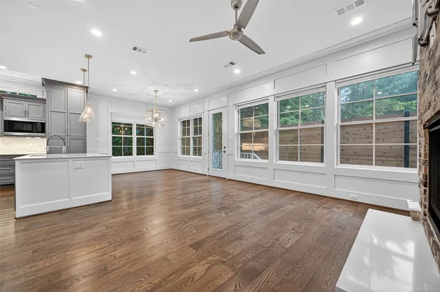 an empty room with wooden floor fireplace and windows