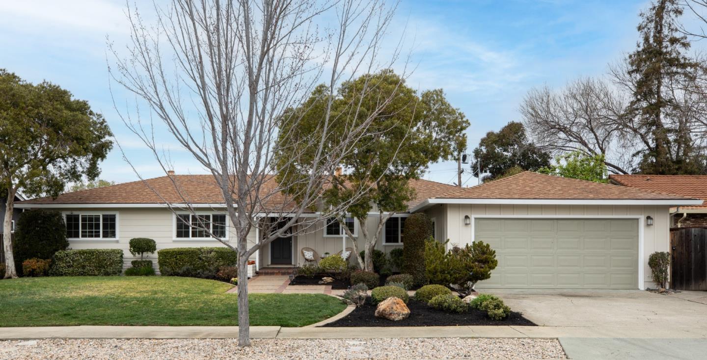 a front view of a house with a garden and trees