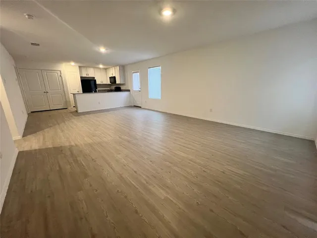 a view of empty room with kitchen and window