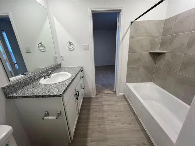 a bathroom with a granite countertop sink and a bathtub