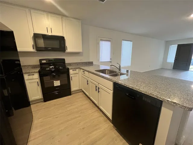 a kitchen with stainless steel appliances granite countertop a stove a sink and a microwave