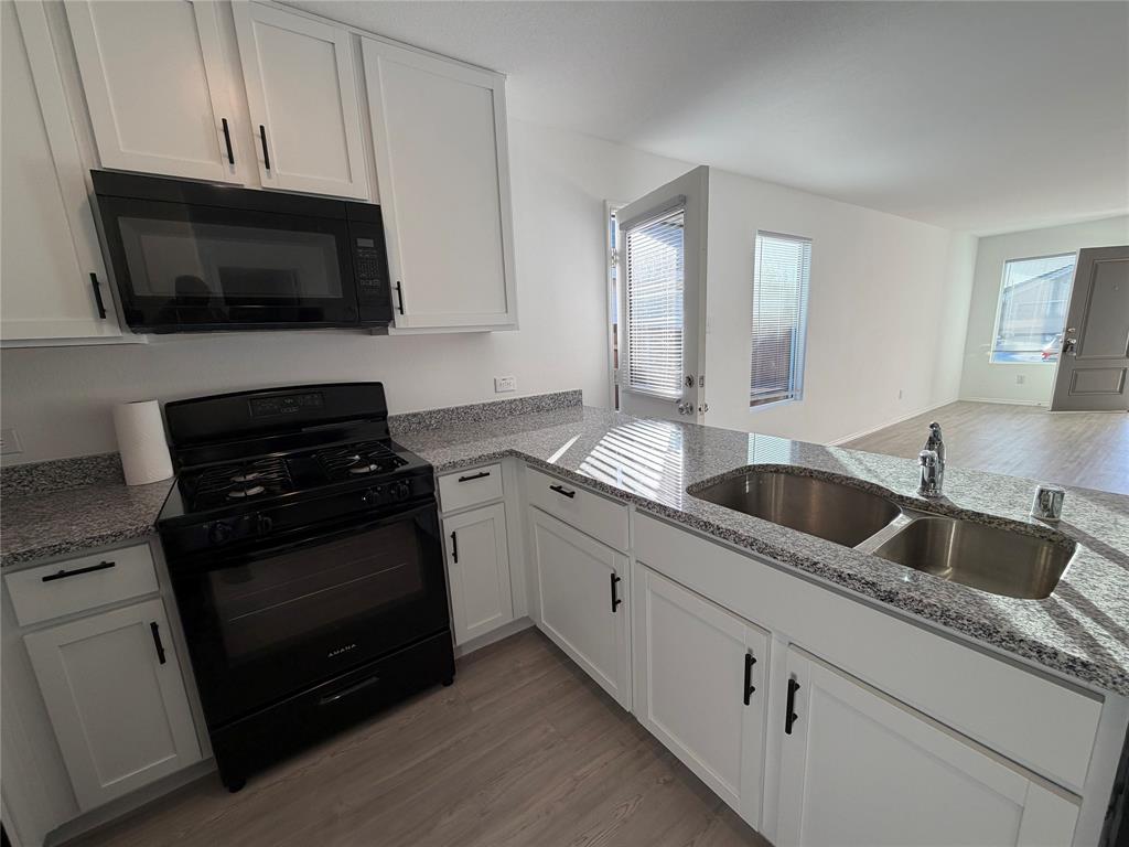 9012 Red Fox Trail McKinney, TX 75071 - Photo 8 of 35 a kitchen with granite countertop white cabinets and black appliances