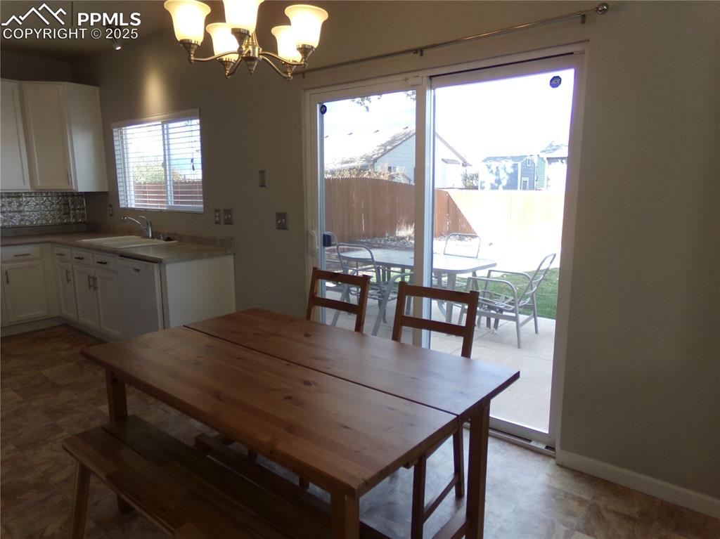 895 Rancher Drive Fountain, CO 80817 - Photo 9 of 29 a dining room with wooden floor a chandelier a wooden table and chairs