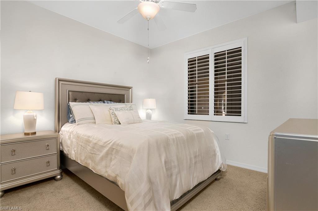 9719 Acqua Court, Unit 214 Naples, FL 34113 - Photo 20 of 50 a large bed sitting in a bedroom next to a window and a chandelier