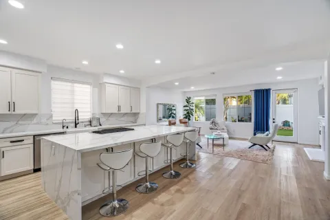 a kitchen with stainless steel appliances a dining table chairs refrigerator sink and cabinets
