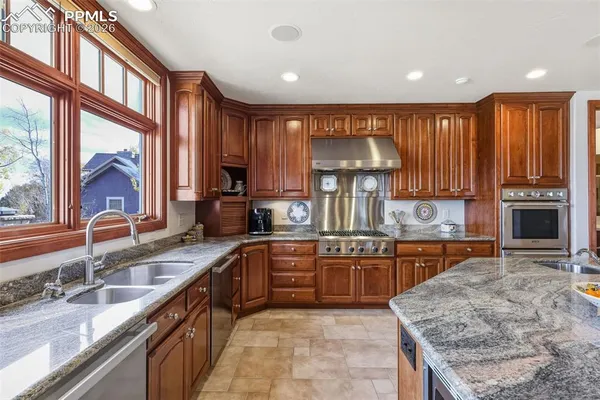 a kitchen with stainless steel appliances granite countertop wooden cabinets a sink and a stove