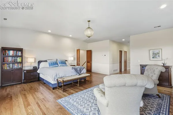 a spacious bedroom with a bed a couch and a bookshelf with wooden floor