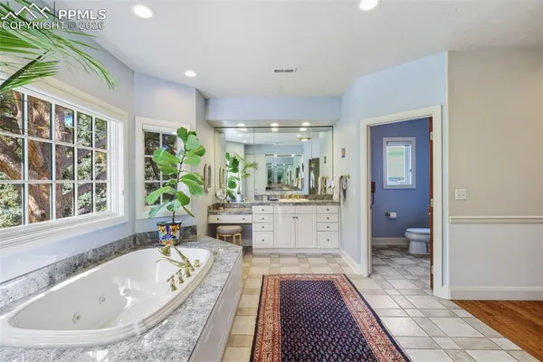 a bathroom with a tub a sink and a large mirror next to a window