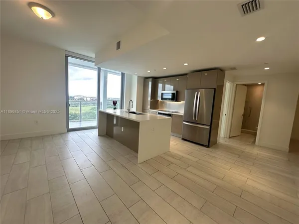 a kitchen with kitchen island granite countertop a sink and a refrigerator