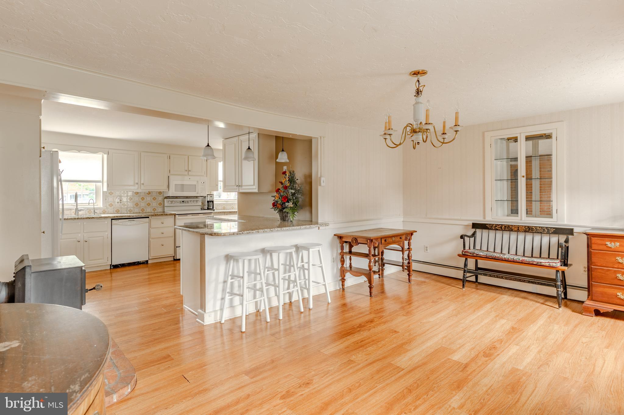 249 Landis Valley Road Lititz, PA 17543 - Photo 59 of 104 a open kitchen with stainless steel appliances kitchen island granite countertop a stove a refrigerator a dining table and chairs with wooden floor