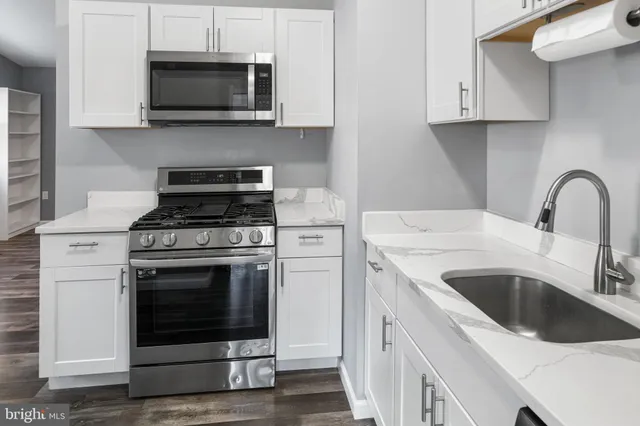 a kitchen with white cabinets stainless steel appliances and a sink