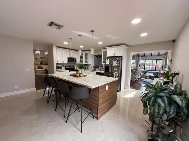 a kitchen with stainless steel appliances kitchen island granite countertop a refrigerator a stove a sink a dining table and chairs