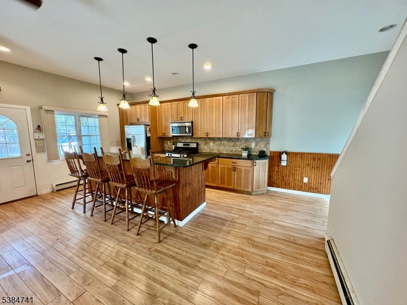 5327 Berkshire Valley Road, Unit 5 Oak Ridge, NJ 07438 - Photo 8 of 32 a kitchen with stainless steel appliances a table chairs sink and cabinets