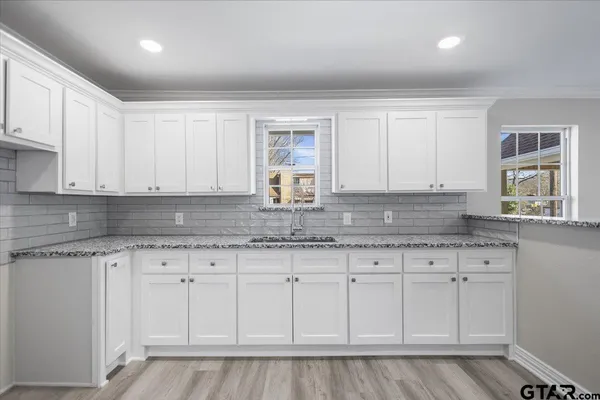 a kitchen with granite countertop white cabinets and sink