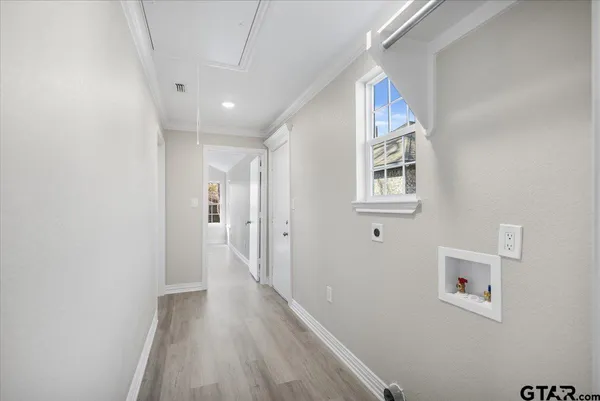a view of a hallway with wooden floor and a bathroom