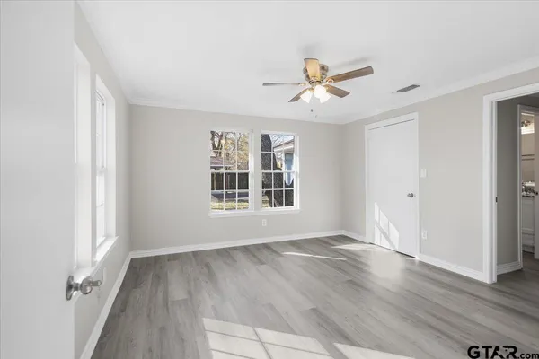 a view of empty room with wooden floor and fan