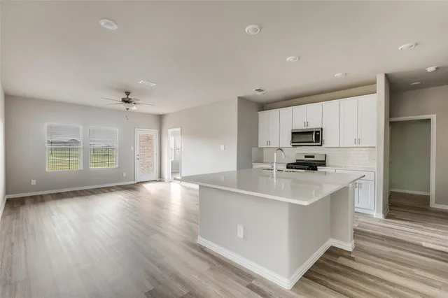 a kitchen with stainless steel appliances a sink a stove a refrigerator cabinets and wooden floor