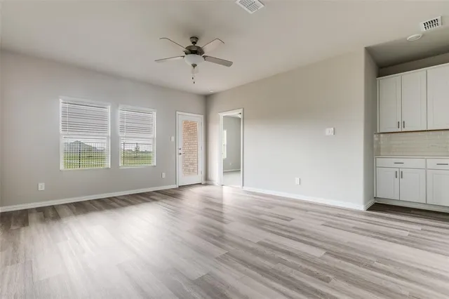 a view of an empty room with a window and wooden floor