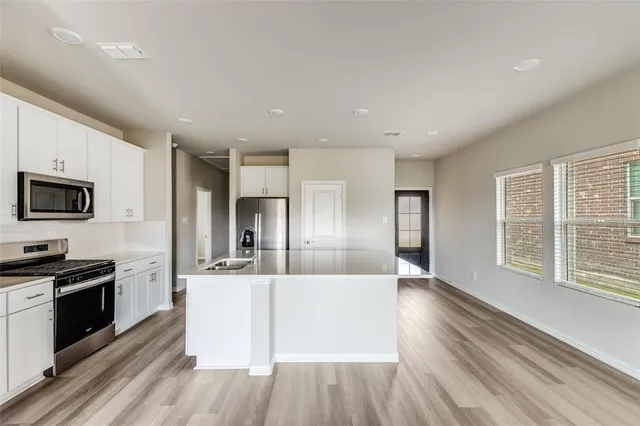 a large kitchen with kitchen island a large counter top space a sink stainless steel appliances and cabinets