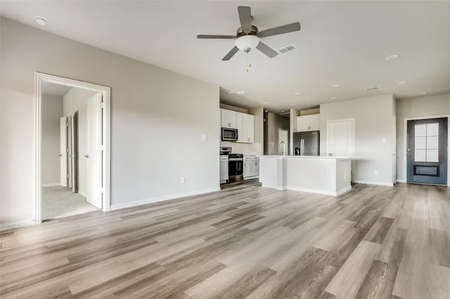 a view of a kitchen with wooden floor and a ceiling fan
