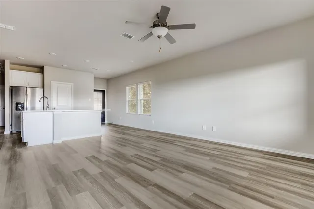 a view of kitchen and empty room with wooden floor