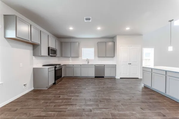 a large white kitchen with kitchen island a sink a stove a refrigerator and white cabinets
