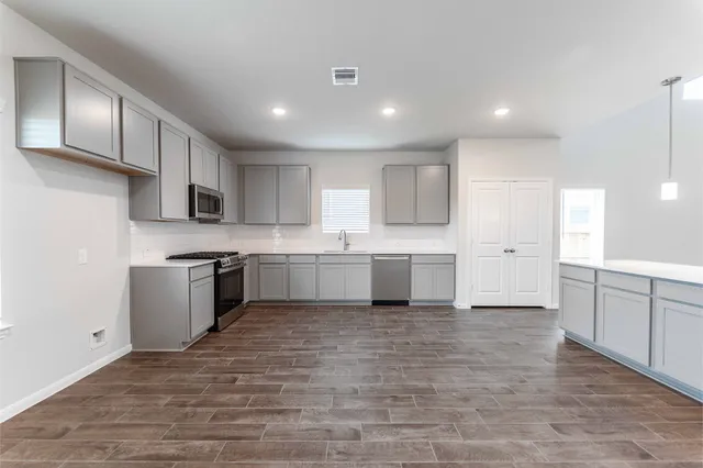 a large white kitchen with kitchen island a sink a stove a refrigerator and white cabinets