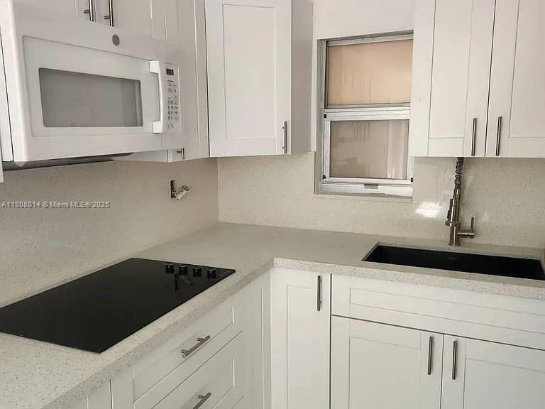 a kitchen with white cabinets a sink and dishwasher