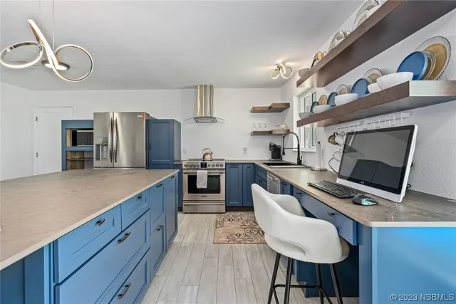 a kitchen with stainless steel appliances granite countertop a stove top oven a sink dishwasher a dining table and chairs with wooden floor