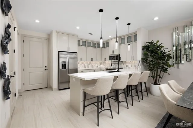 a kitchen with stainless steel appliances kitchen island granite countertop a table chairs and a refrigerator