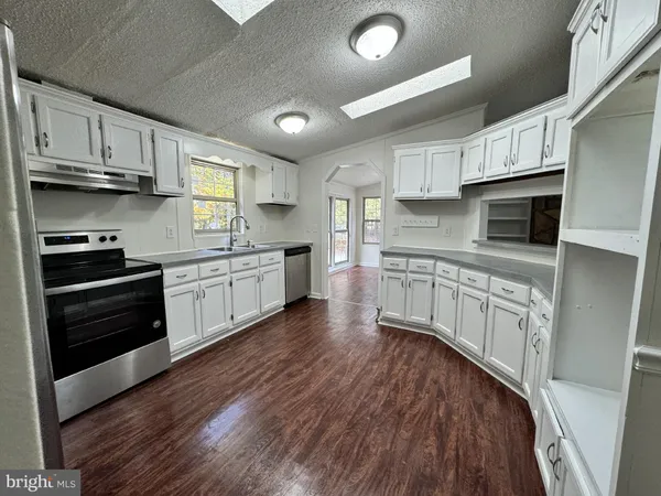a kitchen with stainless steel appliances white cabinets a sink a stove a refrigerator and microwave