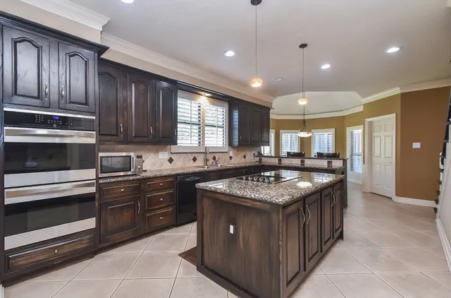 a large kitchen with stainless steel appliances granite countertop a sink stove and refrigerator