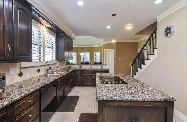a kitchen with granite countertop kitchen island stainless steel appliances a sink stove and cabinets