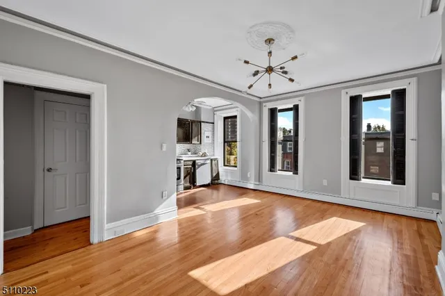 a view of an empty room with window and wooden floor