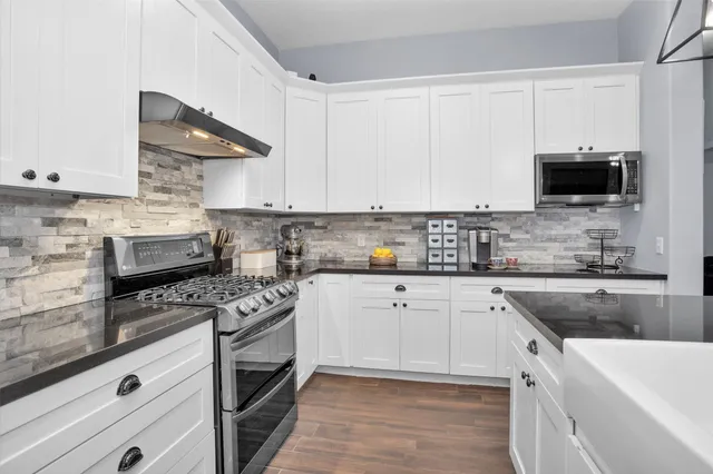 a kitchen with cabinets stainless steel appliances a sink and a stove
