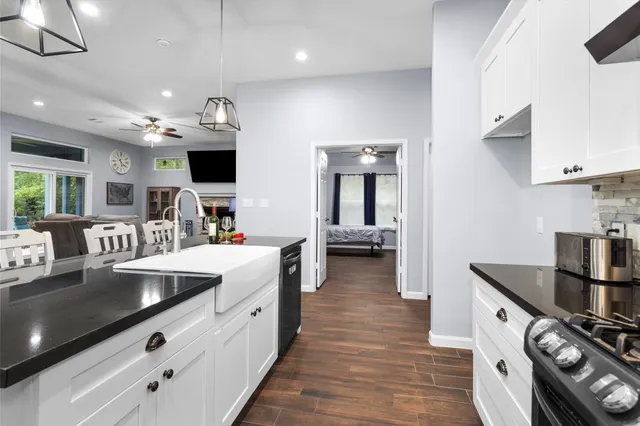 a large white kitchen with stainless steel appliances granite countertop a lot of counter space and a wooden floor