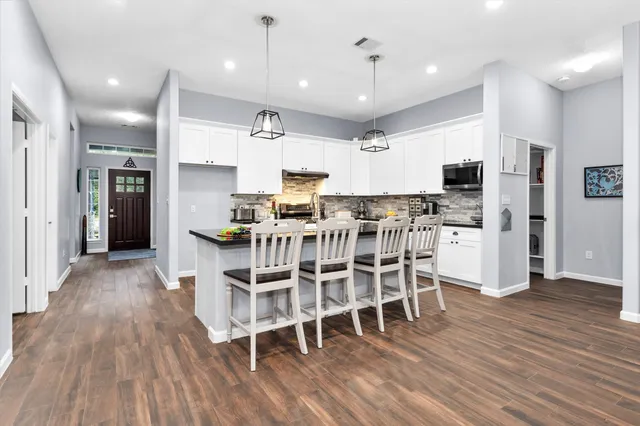 a kitchen with stainless steel appliances kitchen island wooden floors refrigerator and dining table